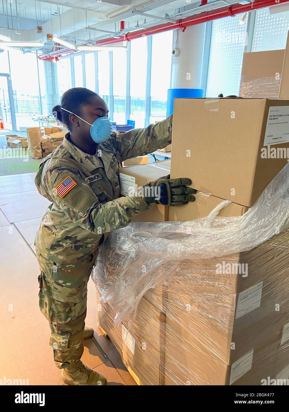 New York Army National Guard Pfc. Daijah Simins, assigned to the 1st Battalion, 258th Field Artillery, part of the 27th Infantry Brigade Combat Team, unloads meals from a pallet at the Staten Island food distribution site April 10, 2020. The meals are placed into a waiting taxi for delivery to quarantined residents unable to leave their homes in New York City. National Guard Soldiers have distributed 714,731 meals across the five boroughs of New York City as part of the National Guard’ support to communities impacted by the COVID-19 pandemic. U.S. National Guard photo by 1st Lt. Nate Sanders. Stock Photo