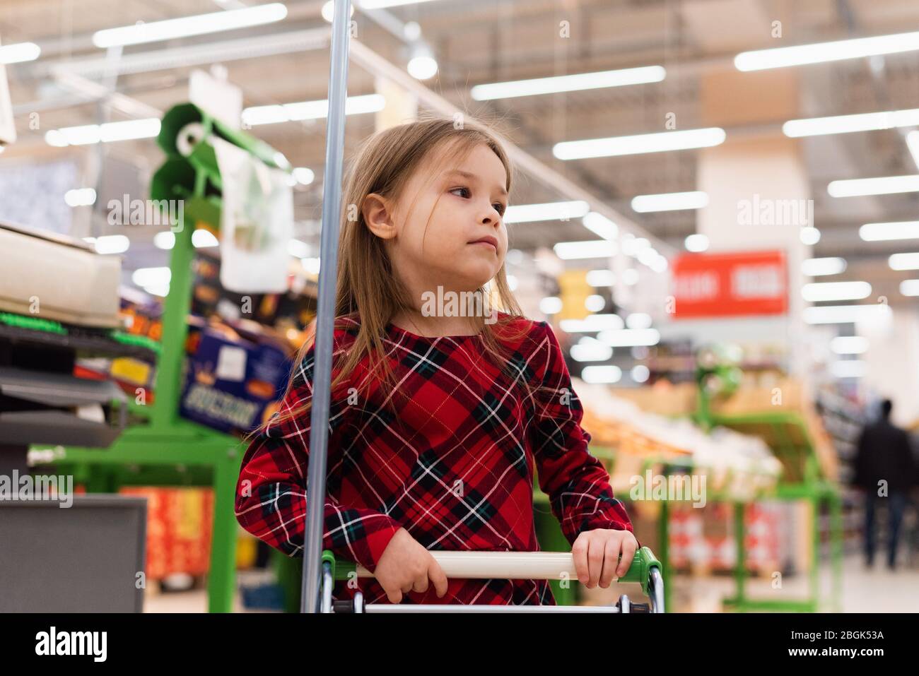 Sales and shopping. Little cute girl with shopping cart standing in