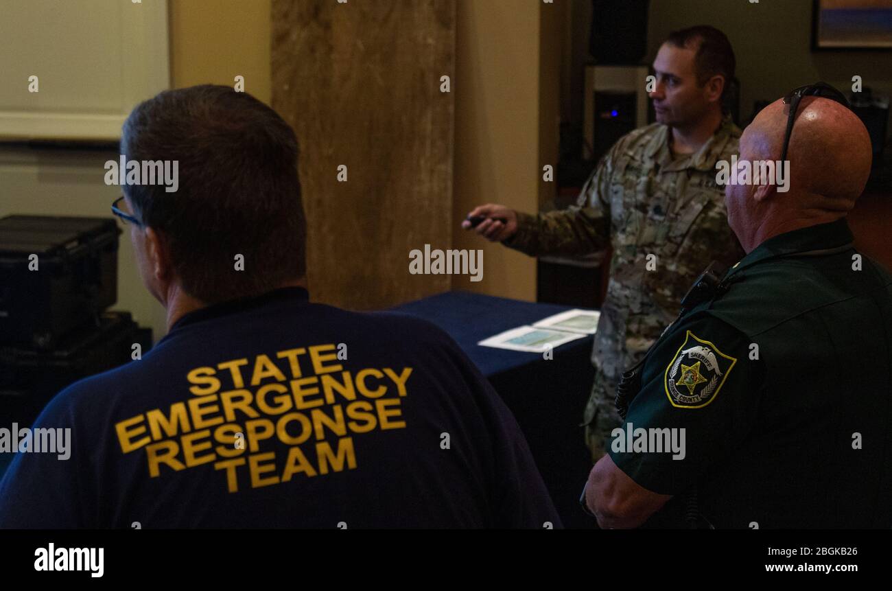 Lt. Col. Robert Harris , commander of the 3rd Battalion, 265th Air Defense Artillery Regiment  briefs members of the Orange County Sheriff's Office and Florida's State Emergency Response Team on plans for the next morning's COVID-19 testing. Stock Photo