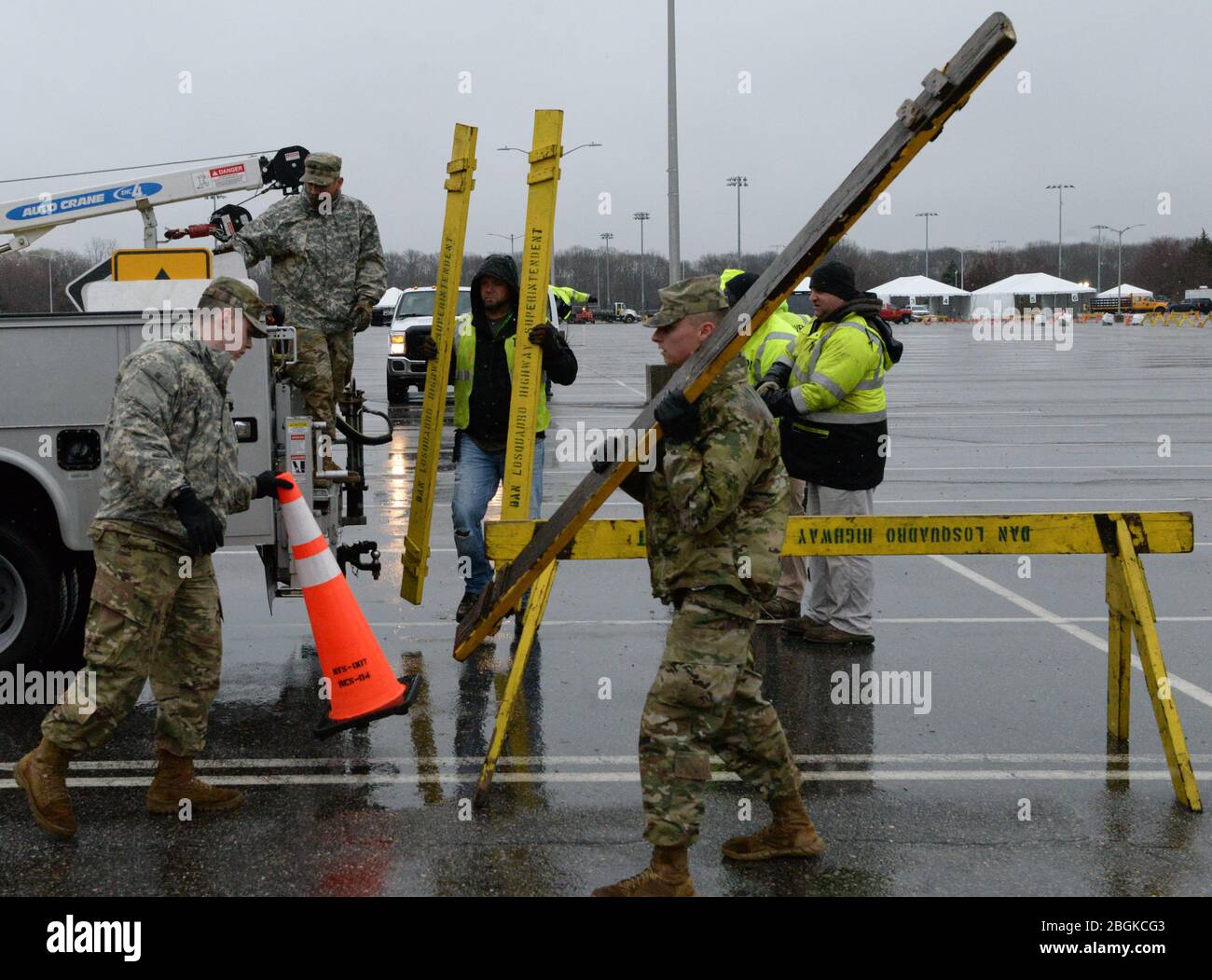 New York Army National Guard members, with Brookhaven Highway Department workers, assemble barricades in a SUNY Stony Brook parking lot in Stony Brook, N.Y., March 17, 2020. The barricades are set up to create lanes for cars at a drive-thru swab collection location as part of the multi-agency response to COVID-19. (U.S. Air National Guard photo by Senior Airman Sean Madden) Stock Photo