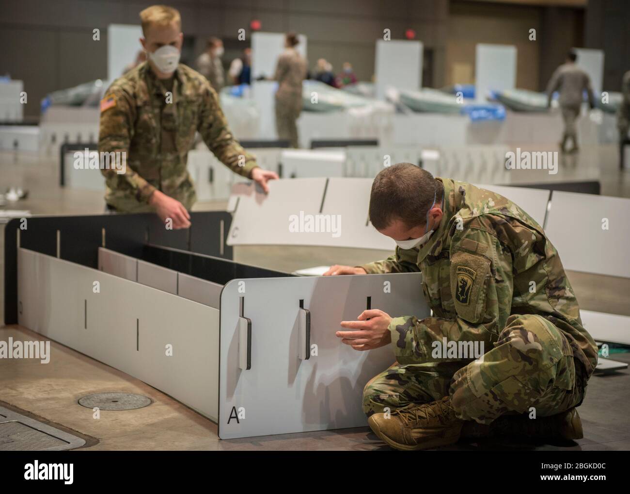 Soldiers from the 1-102nd Infantry Regiment construct a field hospital bed at the Connecticut Convention Center in Hartford, Connecticut, April 11, 2020. Soldiers and Airmen from the Connecticut National Guard are setting up over 600 beds at the site as potential hospital surge capacity for patients recovering from COVID-19. (U.S. Air National Guard photo by Staff Sgt. Steven Tucker) Stock Photo