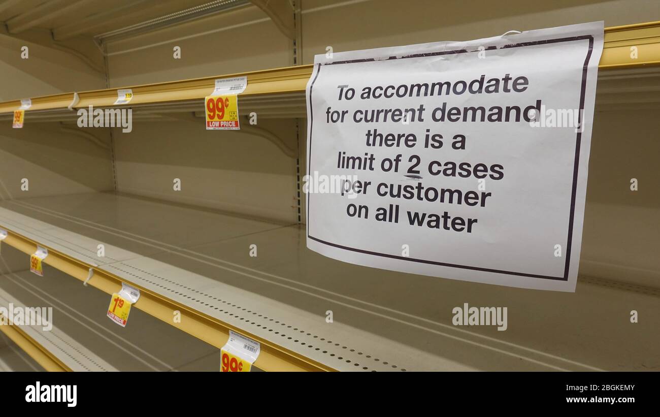 Empty water shelves in a grocery store, with sign limiting purchase. People are hoarding food to prepare for the worst in Coronavirus scare. Stock Photo