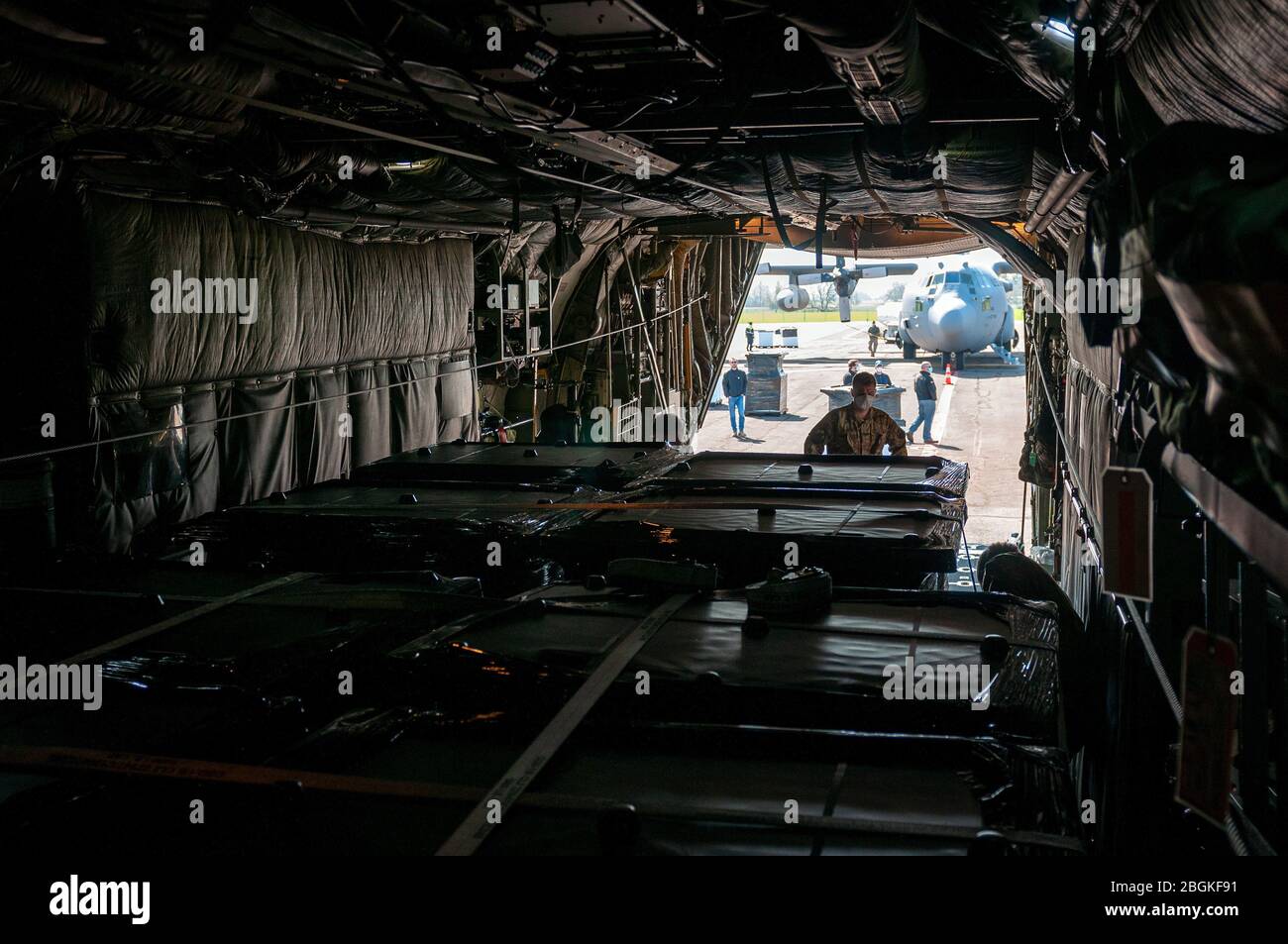 A C-130H Hercules aircrew with the 169th Airlift Squadron, Illinois Air National Guard, loads medical isolation pods onto their aircraft in Eugene, Ore., April 8, 2020. Two 182nd Airlift Wing C-130s airlifted 250 isolation pods in a cross-country, overnight, homeland defense mission delivery to Chicago Midway International Airport for use in the McCormick Place alternative medical facility in the fight against the COVID-19 pandemic. (U.S. Air National Guard photo by Tech. Sgt. Lealan Buehrer) Stock Photo