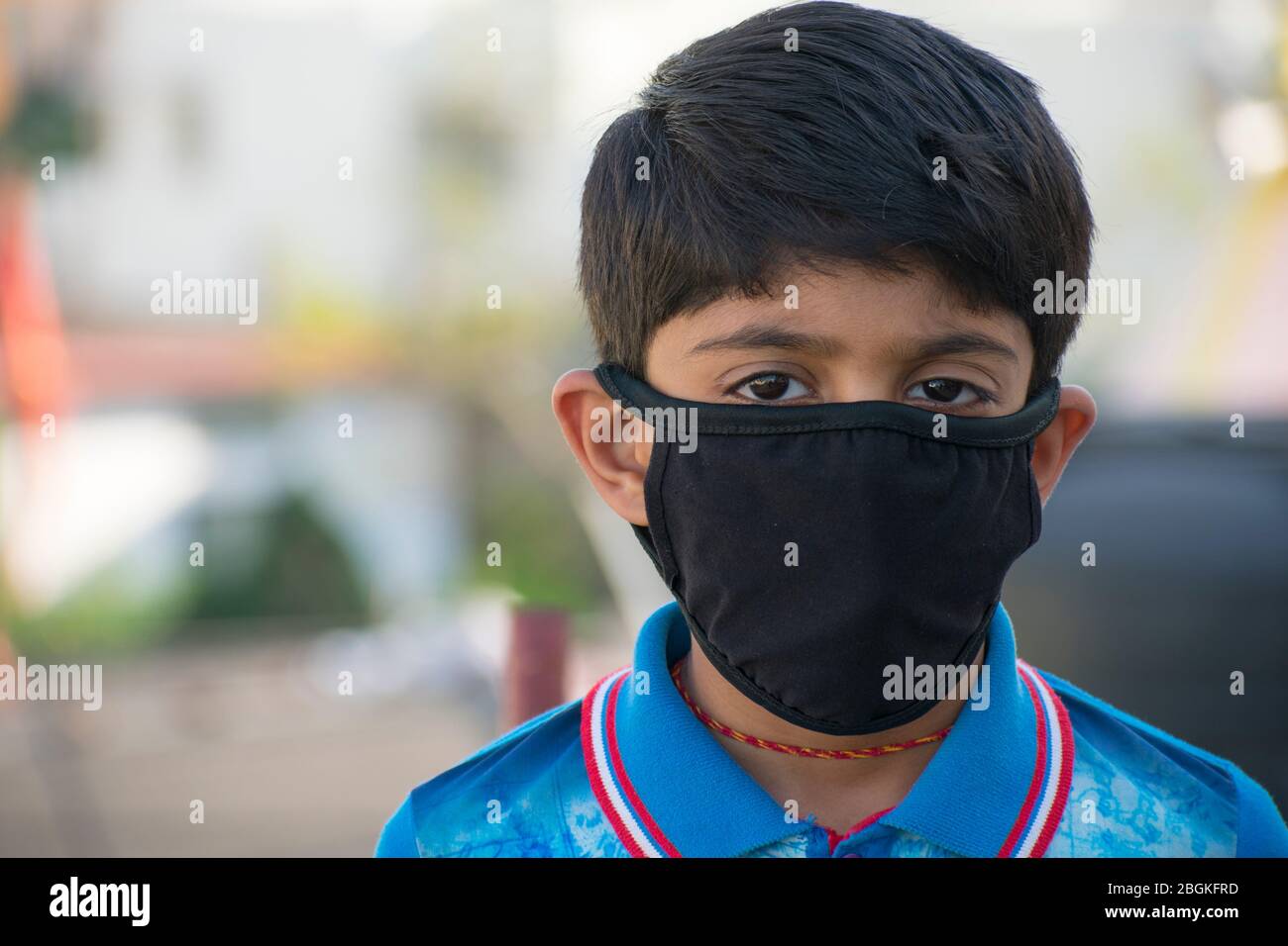 Indian boy wearing a Black face mask. Front face View, blurred