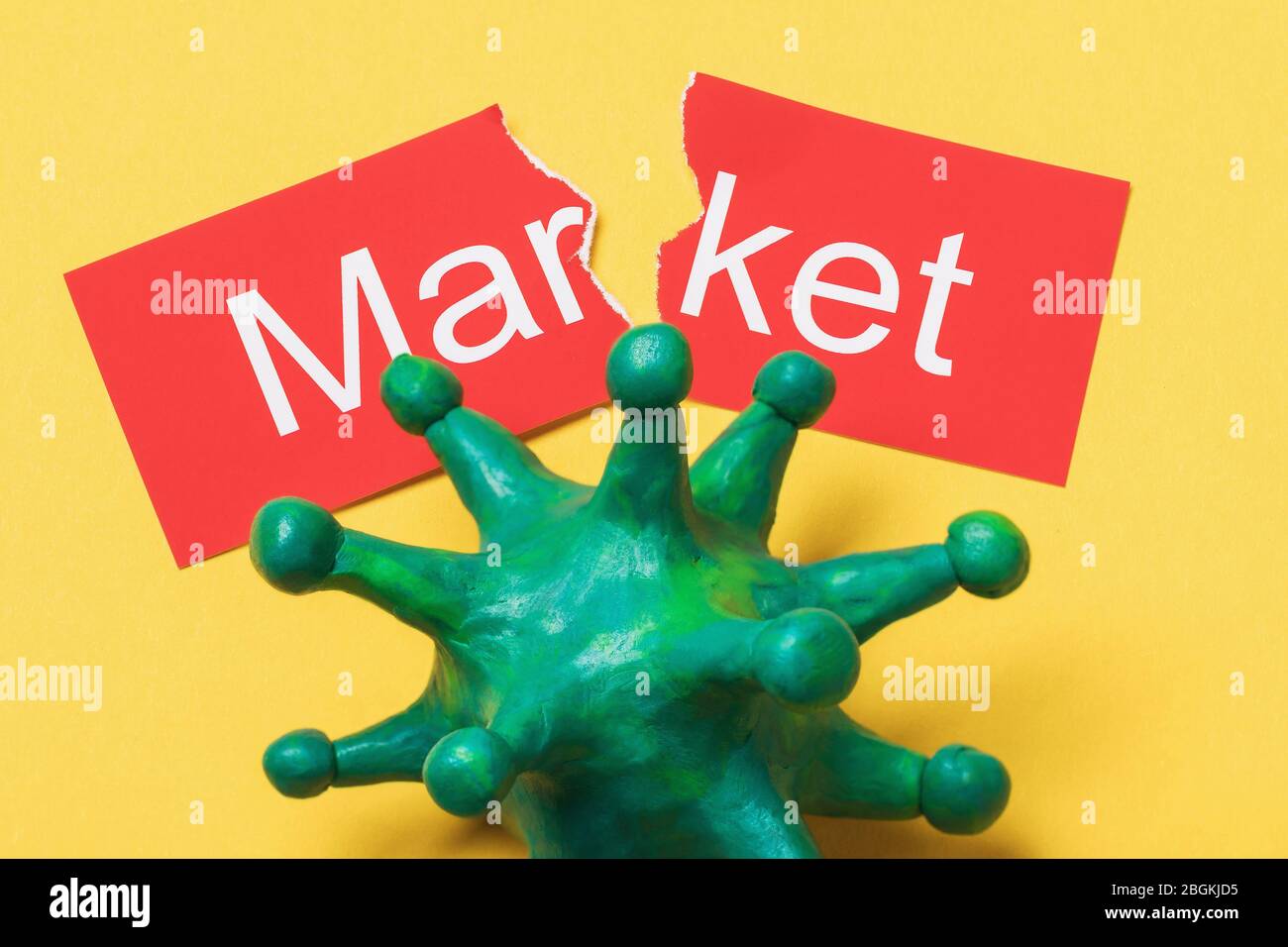 Torn in half tag with text and toy coronavirus. Concept on the impact of the COVID-19 pandemic on the market Stock Photo