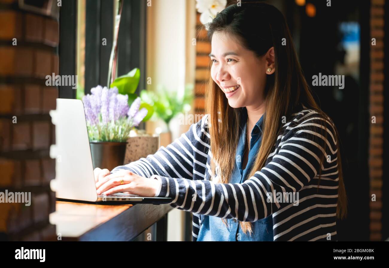 Work from home during the outbreak of the virus. Asian Women Work from home, use a laptop to work. Online Meetings Video Conferrence with the team in Stock Photo
