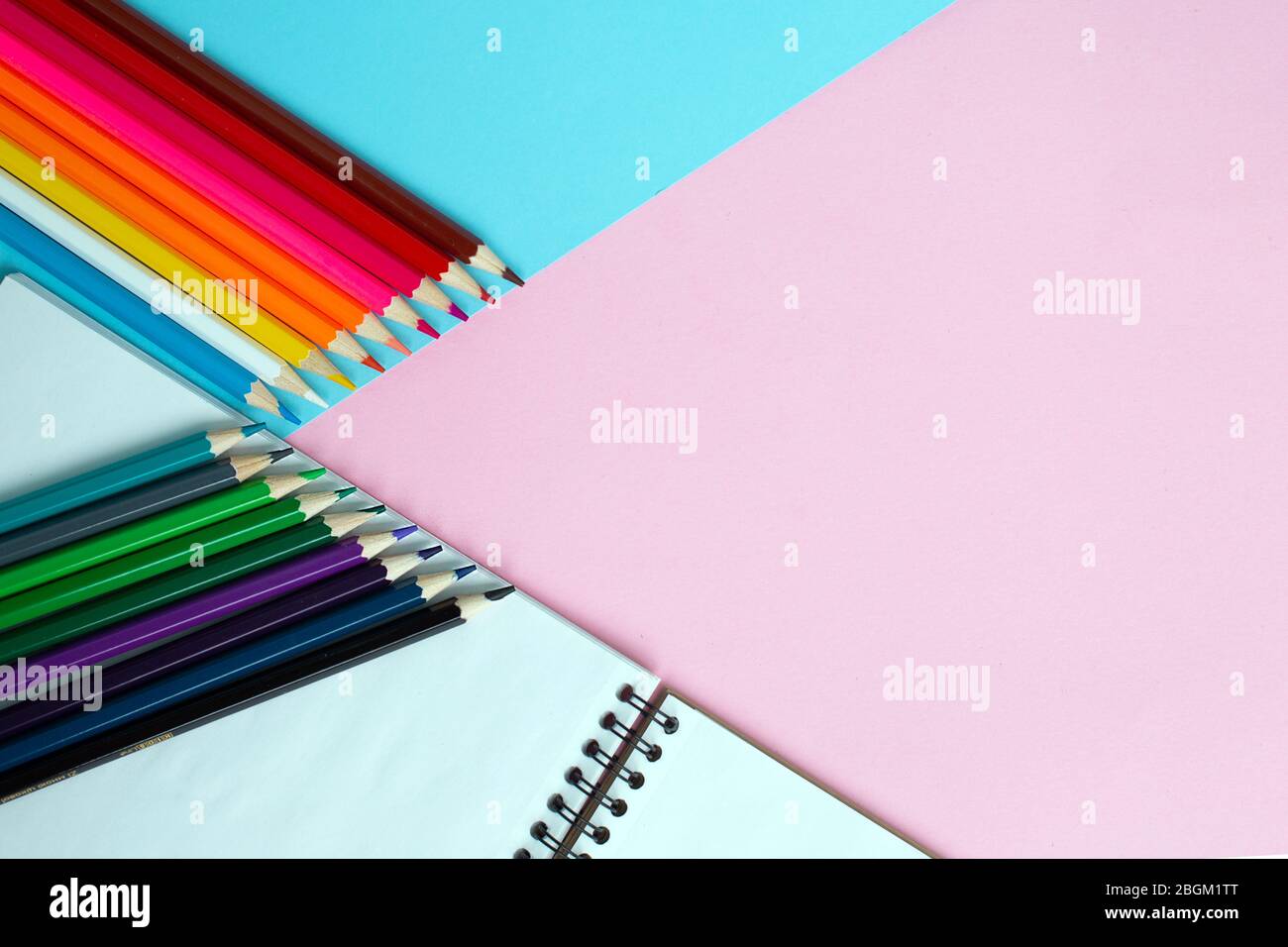 Color pencils and notebook on color background. Stock Photo
