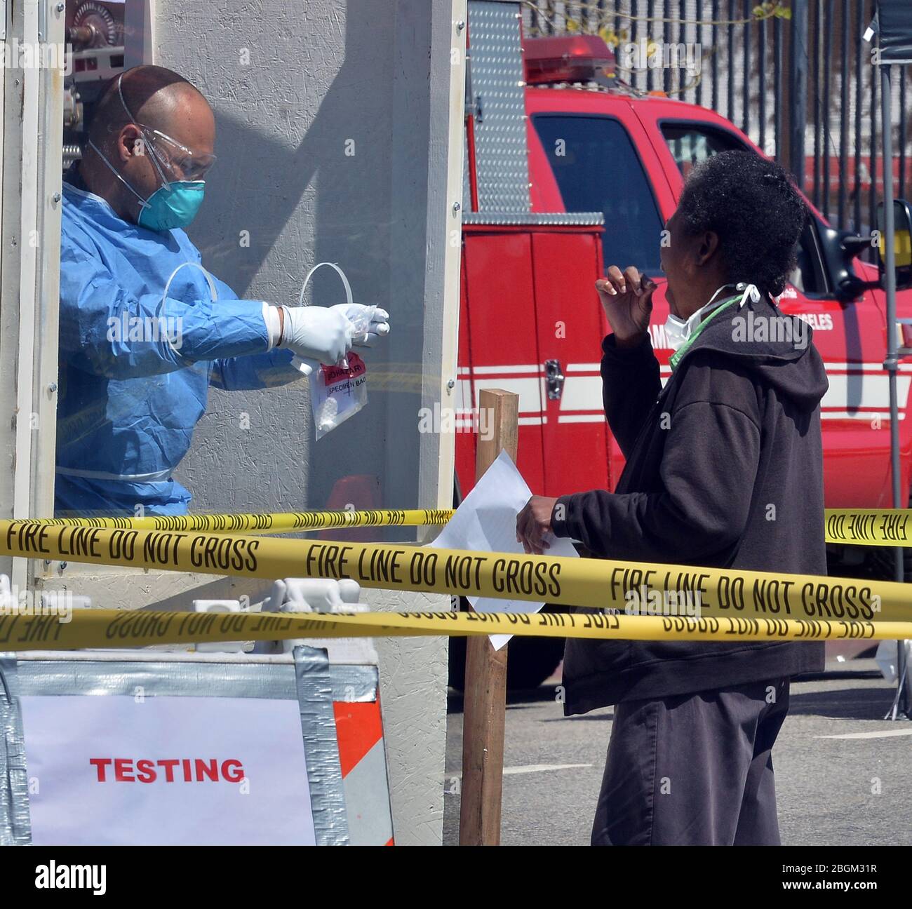 A woman administers a COVID-19 self-testing kit at a LA Fire Department pop-up testing station, where workers in hazmat suits handed out testing swabs to the homeless from behind a protective window in the Skid row section of Los Angeles on Tuesday, April 21, 2020. Forty-three more people have tested positive for the coronavirus at the Union Rescue Mission, Los Angeles' oldest and largest homeless shelter. The sudden spike in cases comes despite the extreme precautions the shelter has been taking to prevent such an outbreak. Photo by Jim Ruymen/UPI Stock Photo