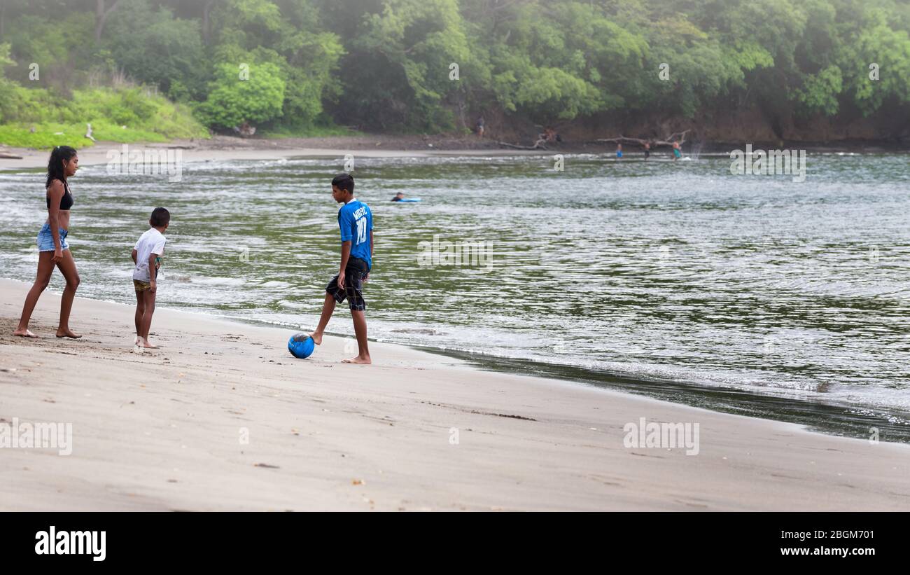 kids playing together on a tropical beach with a forest in background. Playas del Coco, Guanacaste, Costa Rica. Stock Photo