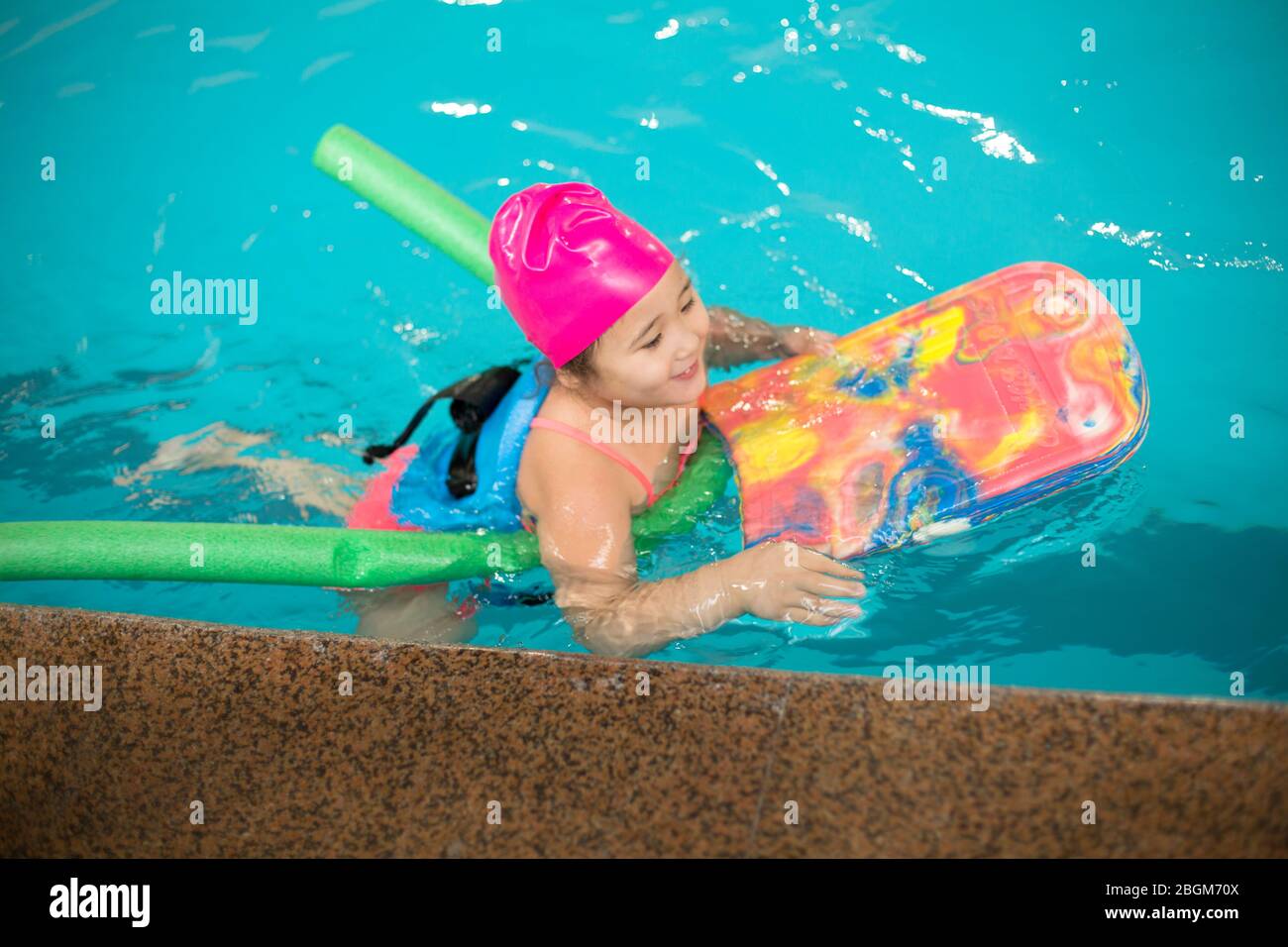 Pretty little girl learning to swim in the pool with swim coach trainer
