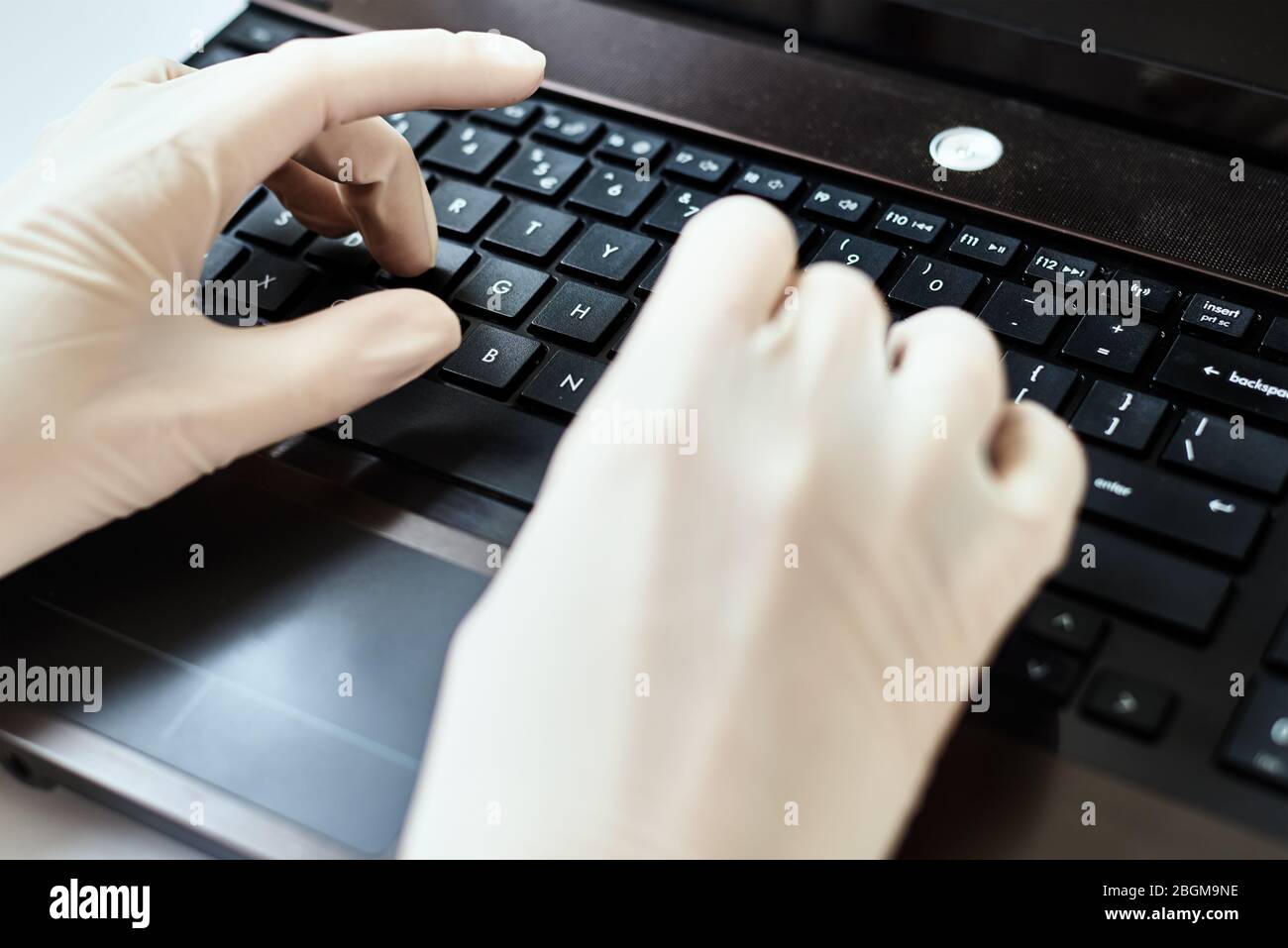 Hands in gloves typing on laptop keyboard. Virus protection concept