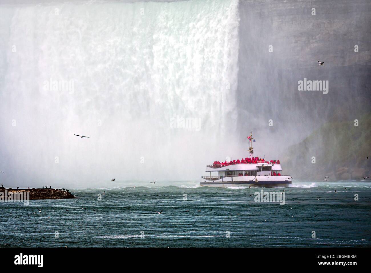 tourist boat in the mist under Horseshoe Falls on the Niagara River Stock Photo
