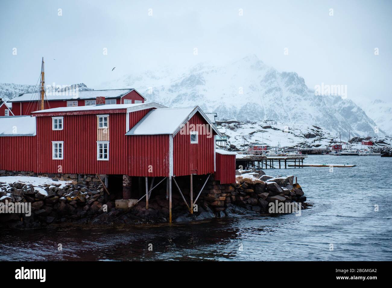 Small red house at the sea among the high fjords of Reine, in Lofoten archipelago, Norway Stock Photo
