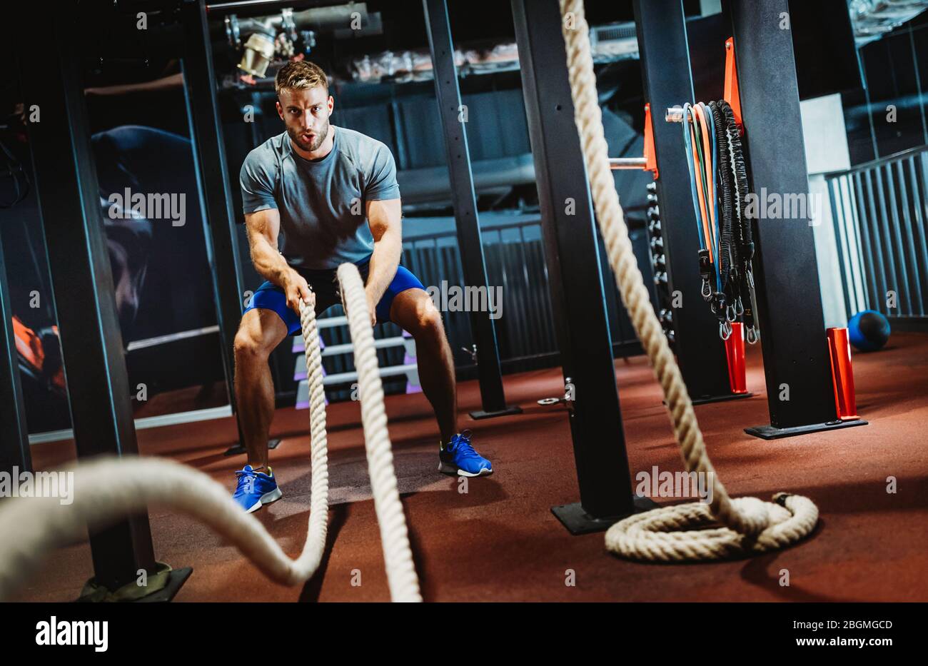 Fit man working out with battle ropes at fitness gym Stock Photo
