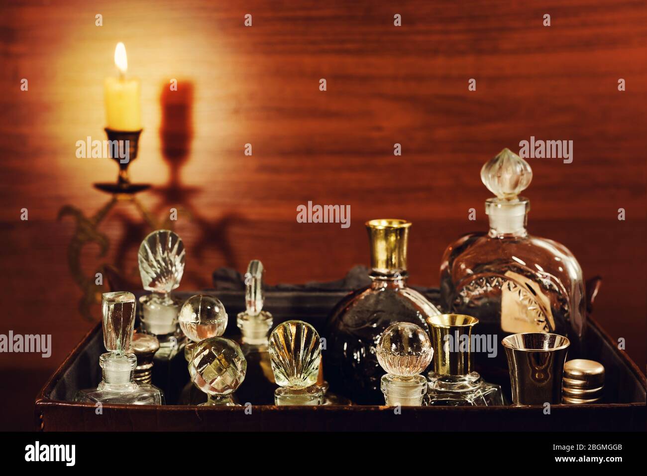 Candlelight in the bronse candlestick and various vintage perfume bottles in the old leather gripsack Stock Photo