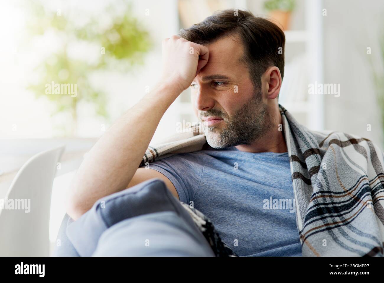 Man feeling discomfort while sitting at home Stock Photo