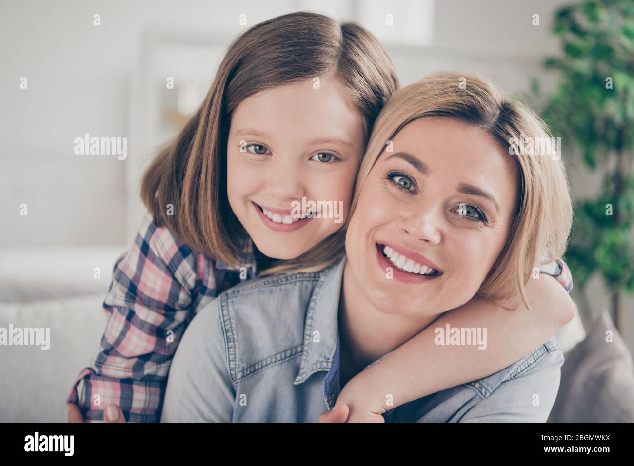 Closeup photo of domestic attractive blond lady mommy daughter comfy couch hugging piggyback stay home quarantine spend weekend together overjoyed Stock Photo