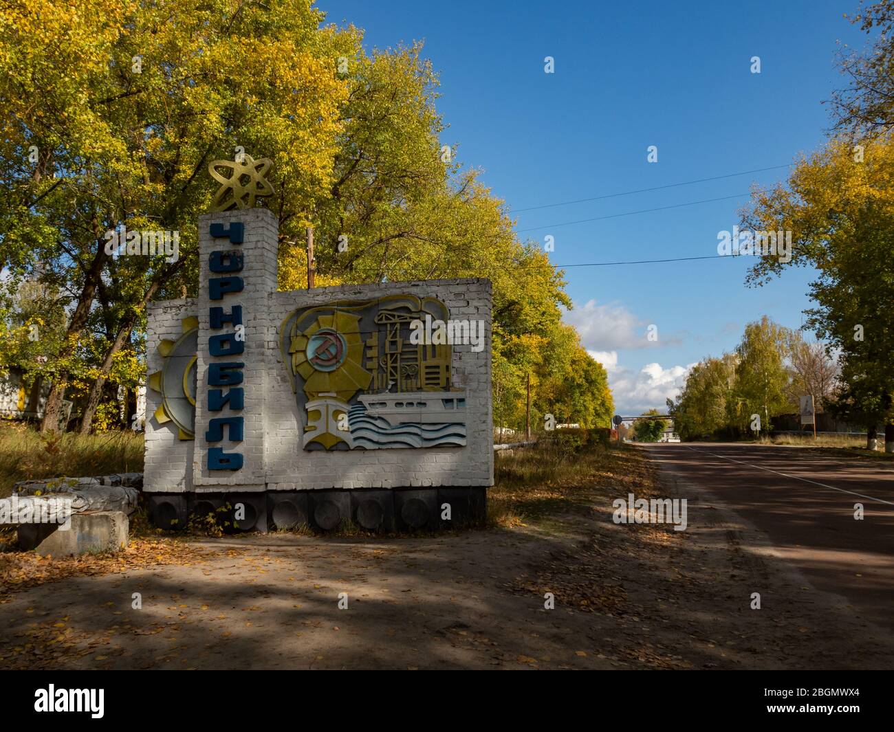 Road and town sign at the entrance of the abandoned city of Chernobyl in the Ukraine, the sign shows the name Chernobyl in Cyrillic letters in vertica Stock Photo