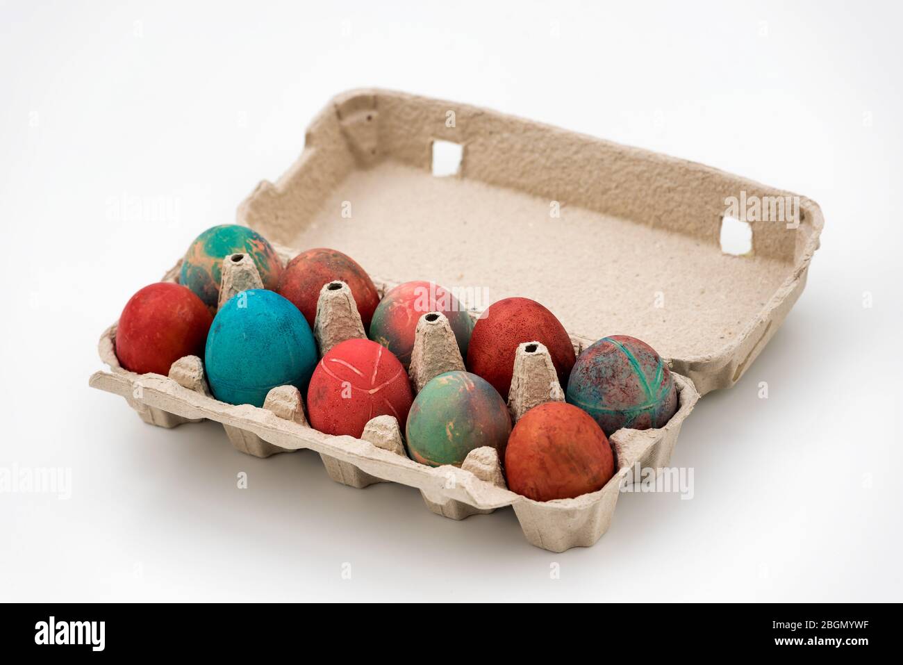 Colorful Easter eggs in cardboard egg box on white background. Raw chicken eggs in open egg box on a white background. Eggs in the package. Stock Photo