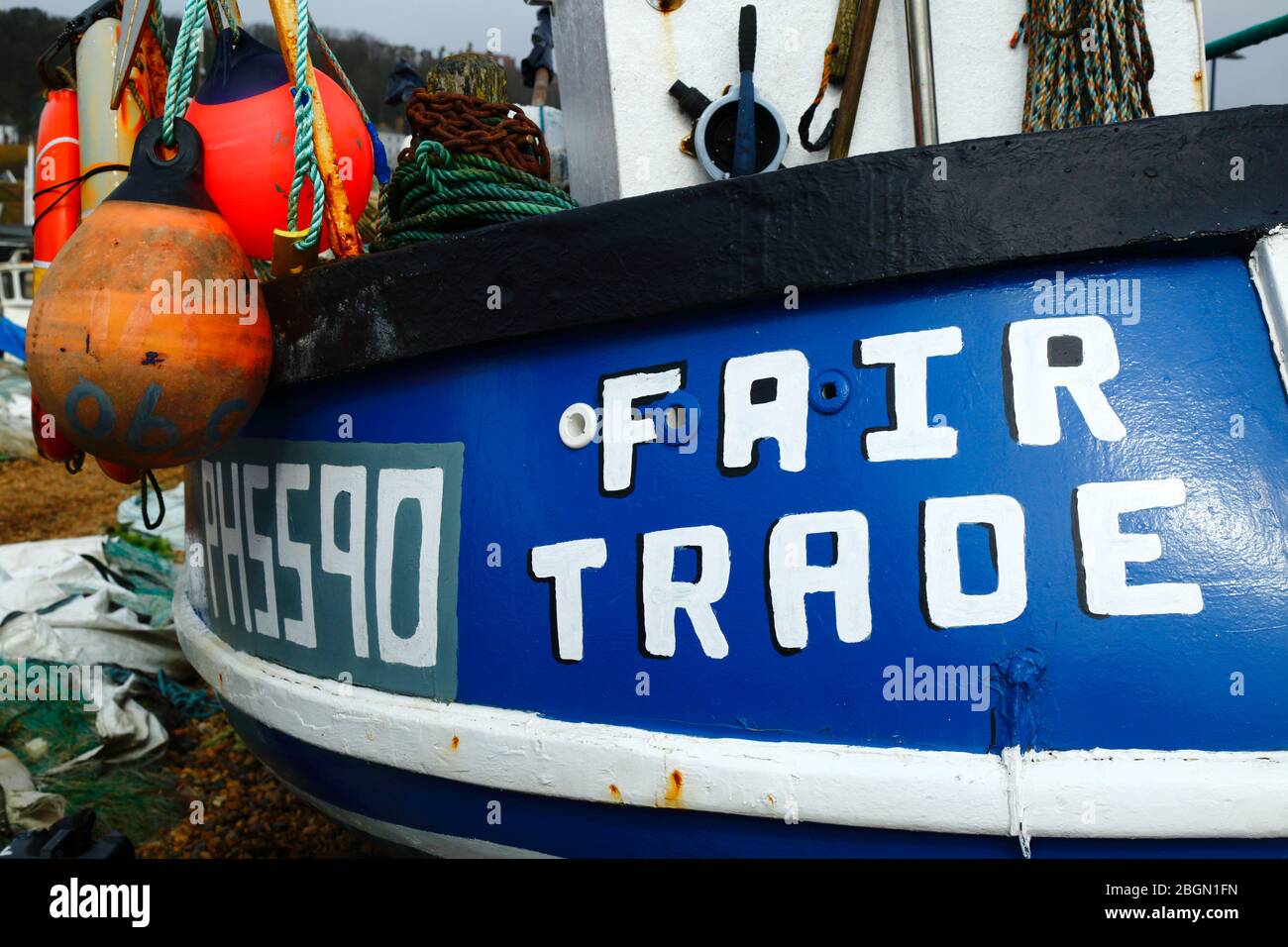 Fair Trade fishing boat on The Stade shingle beach below East Hill cliffs, Hastings, East Sussex, England, UK Stock Photo