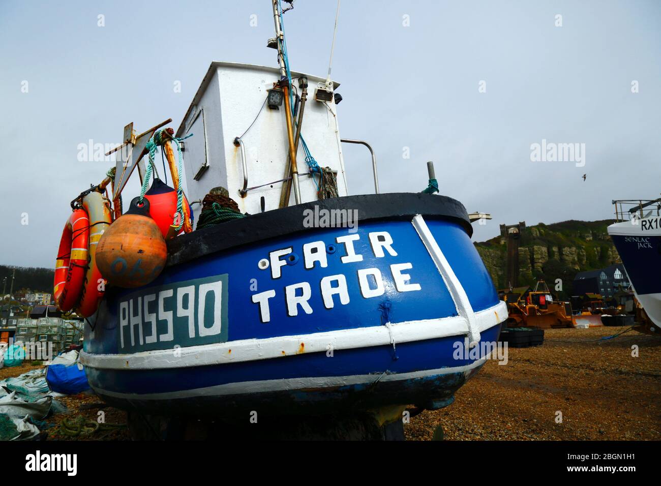 Fair Trade fishing boat on The Stade shingle beach below East Hill Cliff, Hastings, East Sussex, England, UK Stock Photo