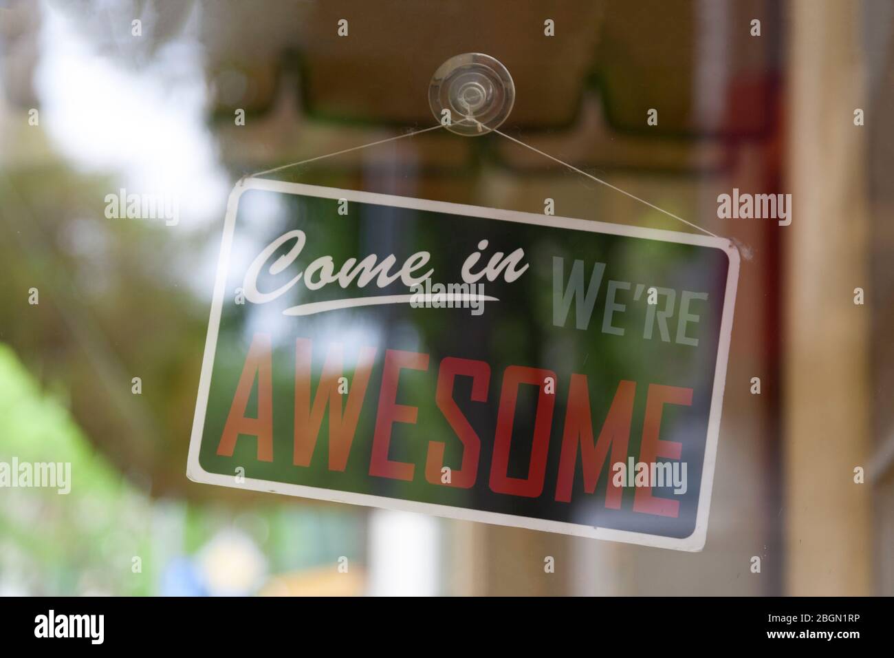Close-up on an open sign in the window of a shop saying 'Come in, we're awesome'. Stock Photo