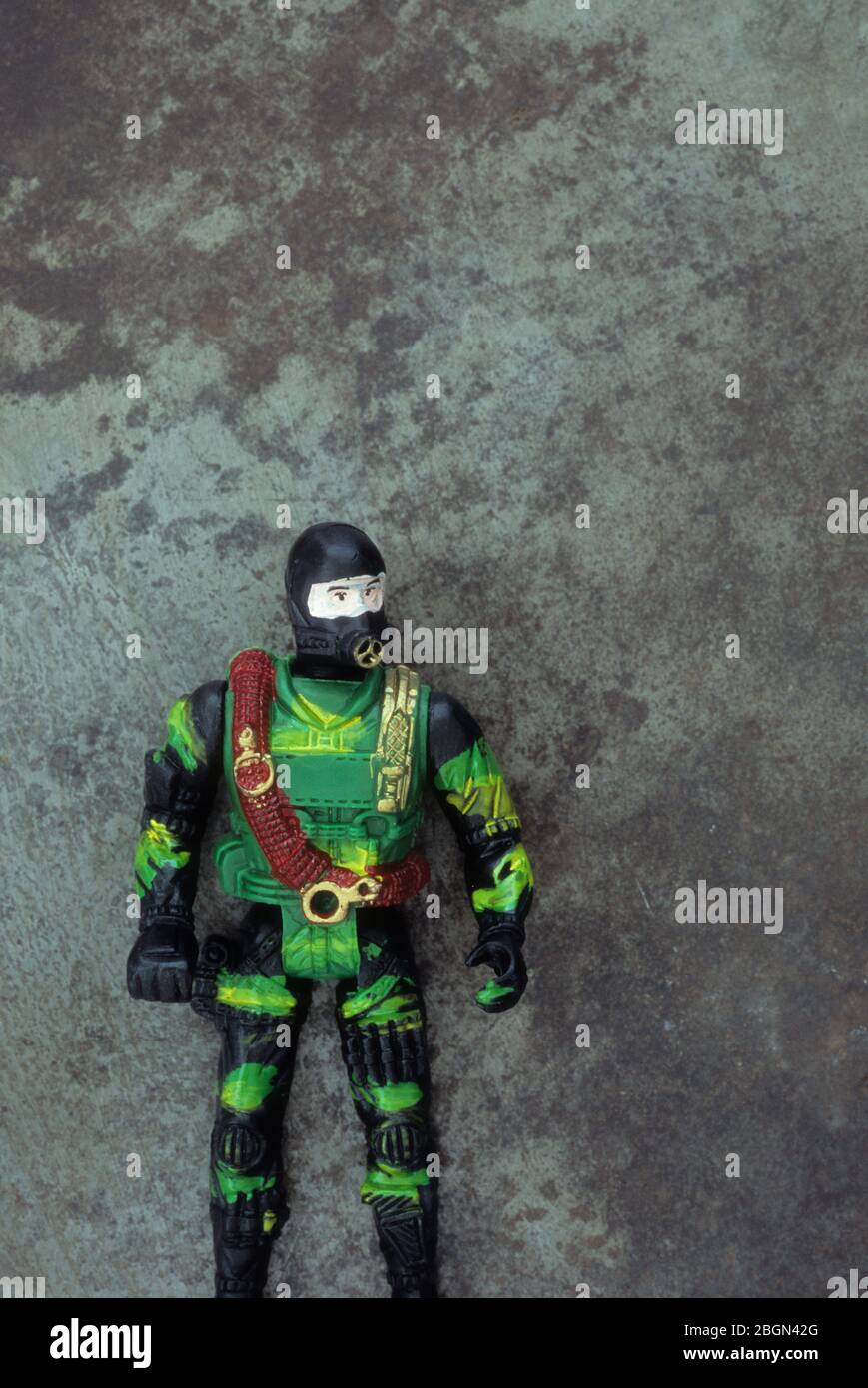 Plastic toy model of diver in camouflaged commando gear with tarnished metal background Stock Photo