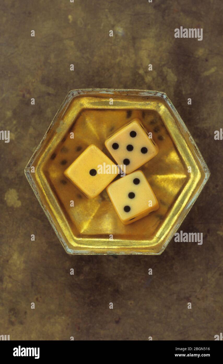 Small hexagonal brass box containing three vintage dice showing numbers 1 and 3 and 5 Stock Photo