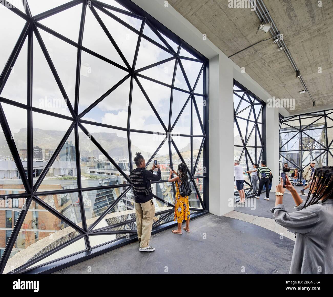 Interior view of cut-glass-faceted windows with visitors taking  photographs. Zeitz MOCAA, Cape Town, South Africa. Architect: Heatherwick Studio, 201 Stock Photo
