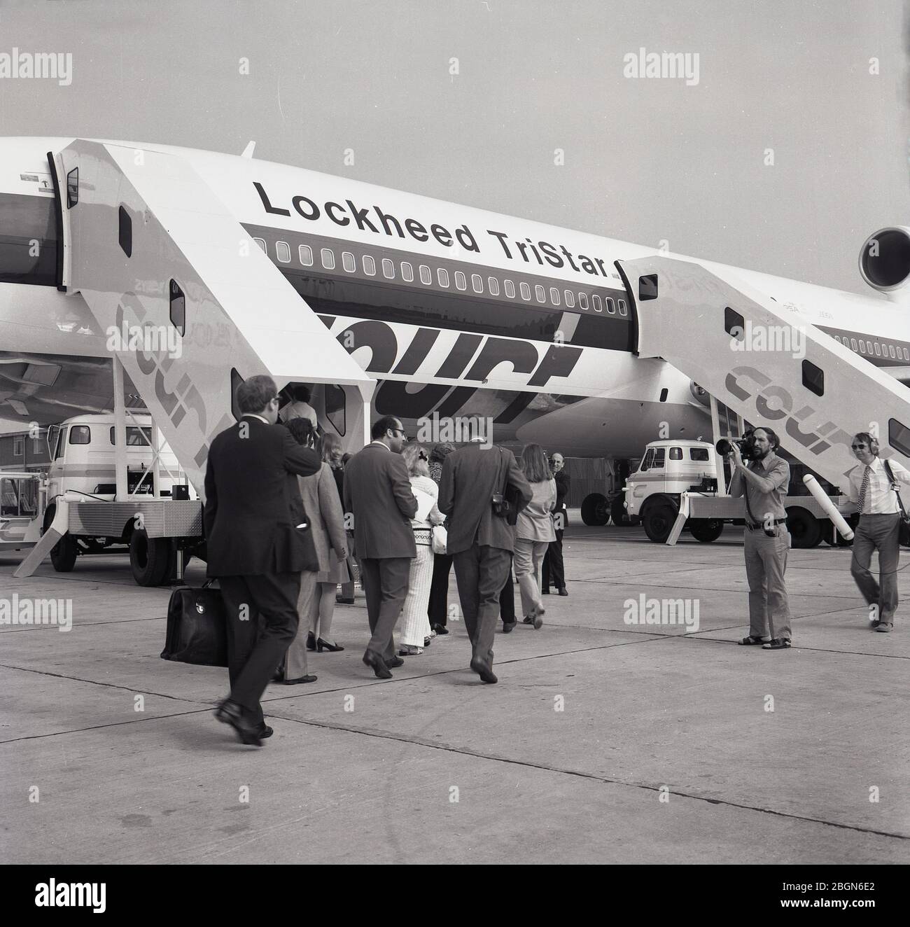 1973, historical, television cameras filming passengers boarding a Lockheed Tristar airplance (L-1011), at the time, the most technologically-advanced widebody commercial aircraft in the world. Court Line Aviation, a British holiday charter company, was the first European airline to operate the Lockheed widebody, powered by the Rolls-Royce RB211 engine, a three-spool engine capable of generating powerful thrust. Stock Photo
