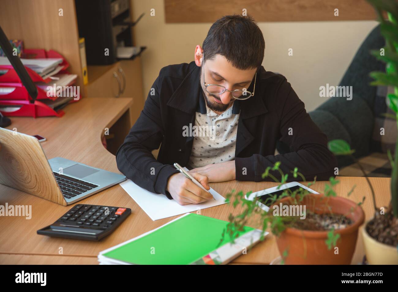 Paperwork. Caucasian entrepreneur, businessman, manager working concentrated in office. Looks serios and busy, wearing classic attire. Concept of work, finance, business, success, leadership. Stock Photo