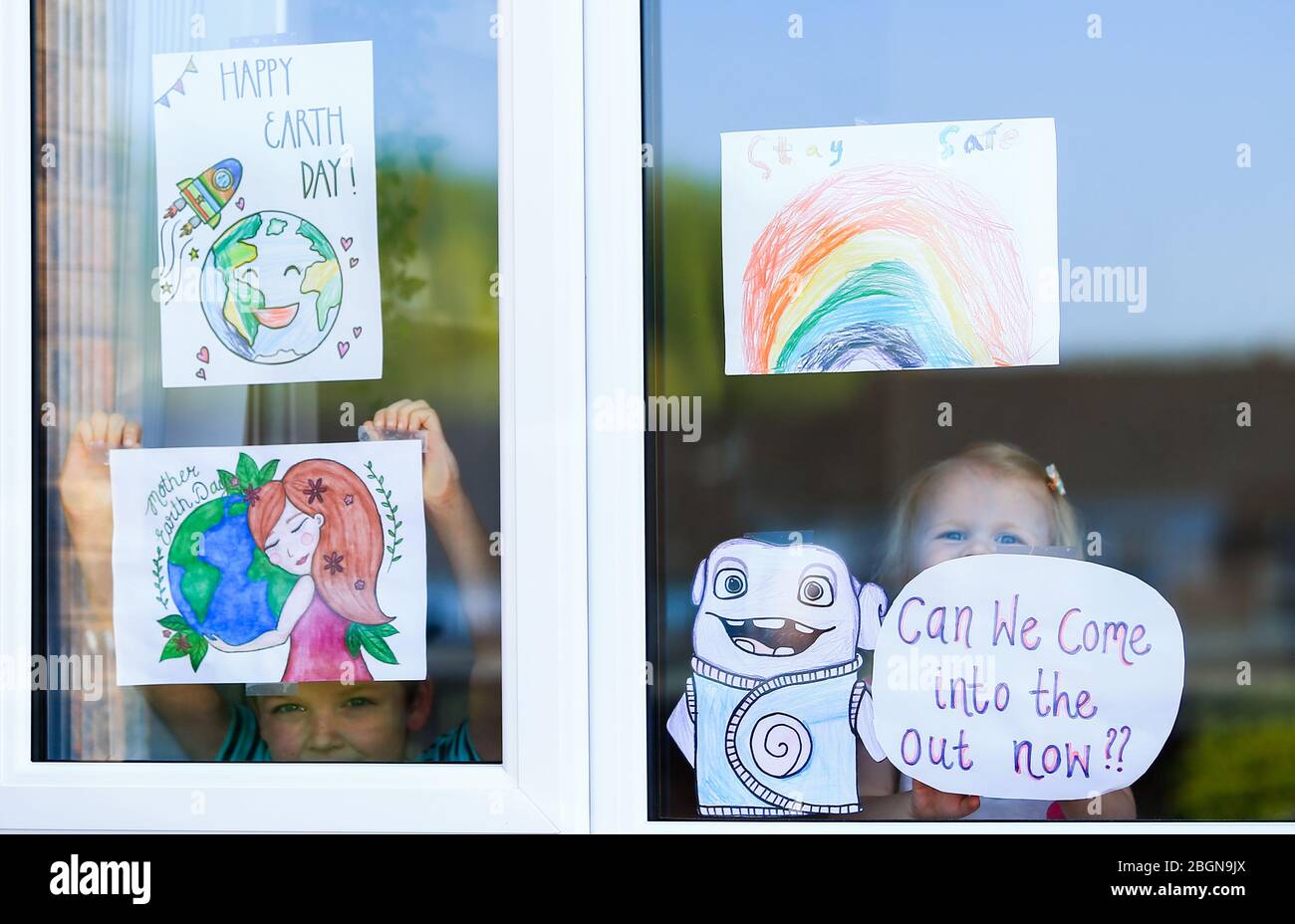 Droitwich, Worcestershire, UK. 22nd Apr, 2020. 7-year-old Will Keight appears at the window of his house in Droitwich Spa with his young sister Orla, 2, with the posters they have made for World Earth Day and the NHS. [Note: parental permission granted] Credit: Peter Lopeman/Alamy Live News Stock Photo