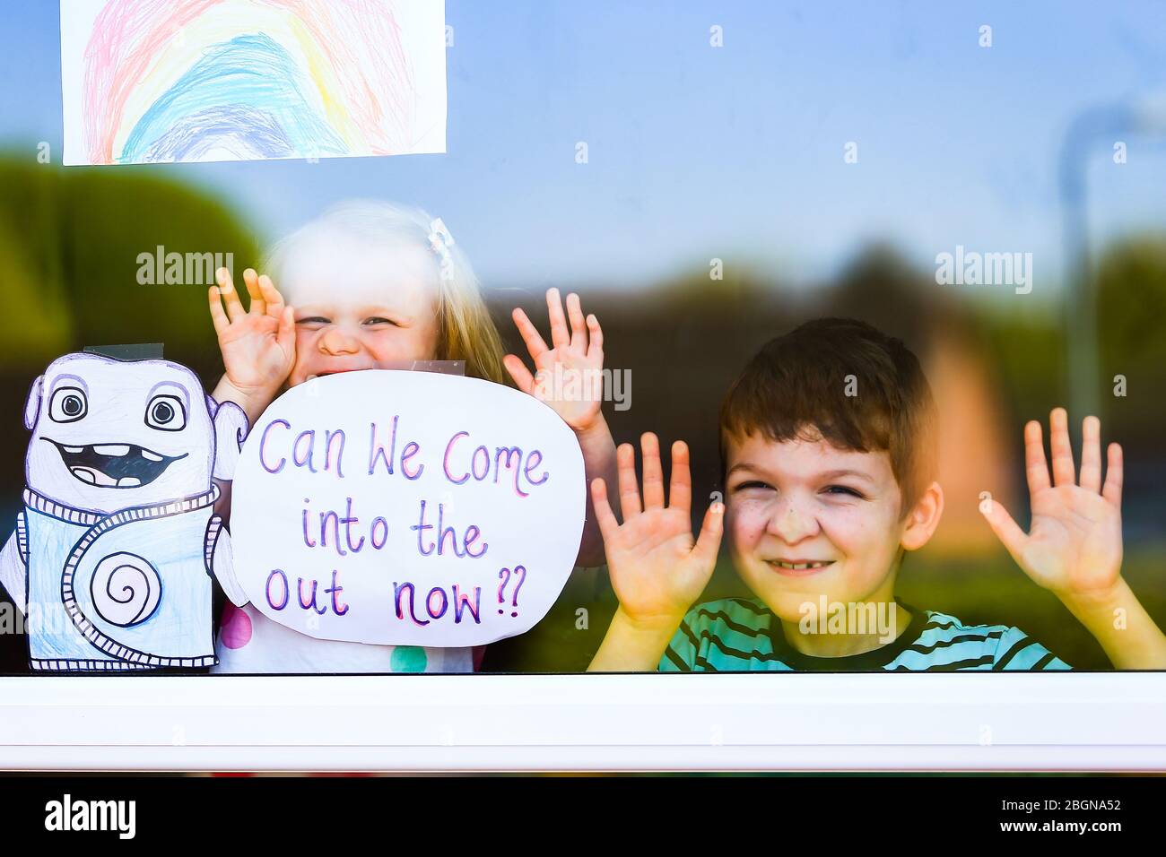 Droitwich, Worcestershire, UK. 22nd Apr, 2020. 7-year-old Will Keight appears at the window of their home in Droitwich Spa with his young sister Orla, 2, with the posters they have made for World Earth Day and the NHS. [Note: parental permission granted] Credit: Peter Lopeman/Alamy Live News Stock Photo