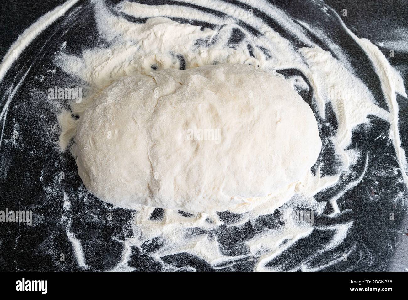 Close up of powdered white dough for cooking bread. White round handmade dough on a kitchen table Stock Photo