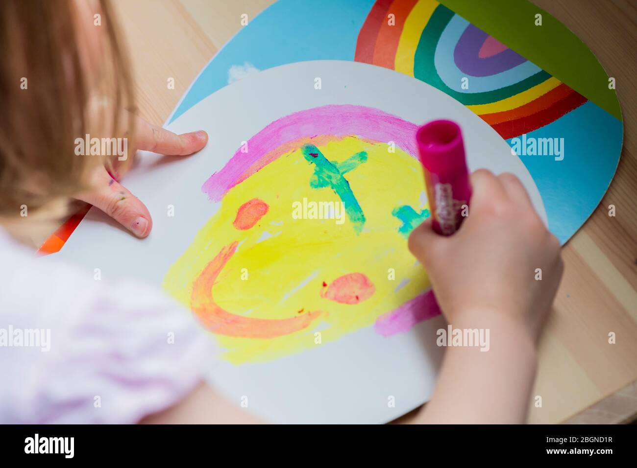 A young girl paints a smiley face while home schooling Stock Photo