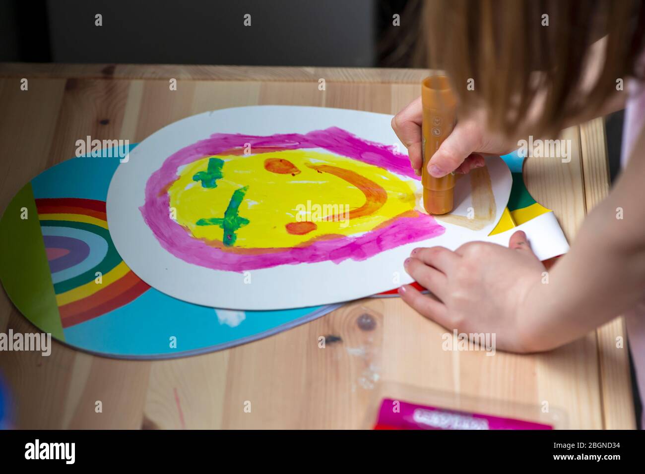 A young girl paints a smiley face while home schooling Stock Photo