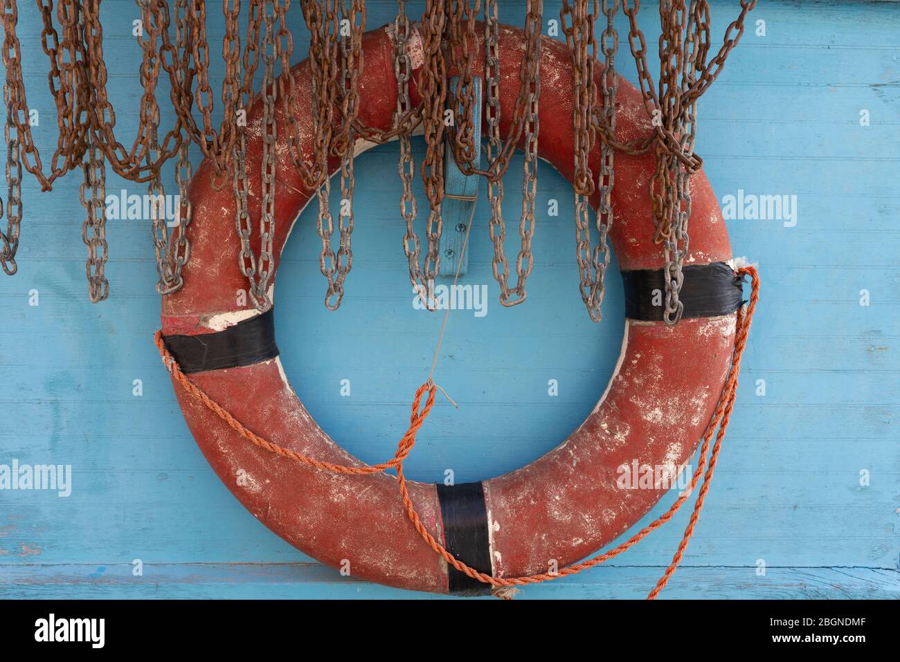 An aging lifebuoy stands ready for use despite evident signs of a long, hard life exposed to the seaside elements. Stock Photo