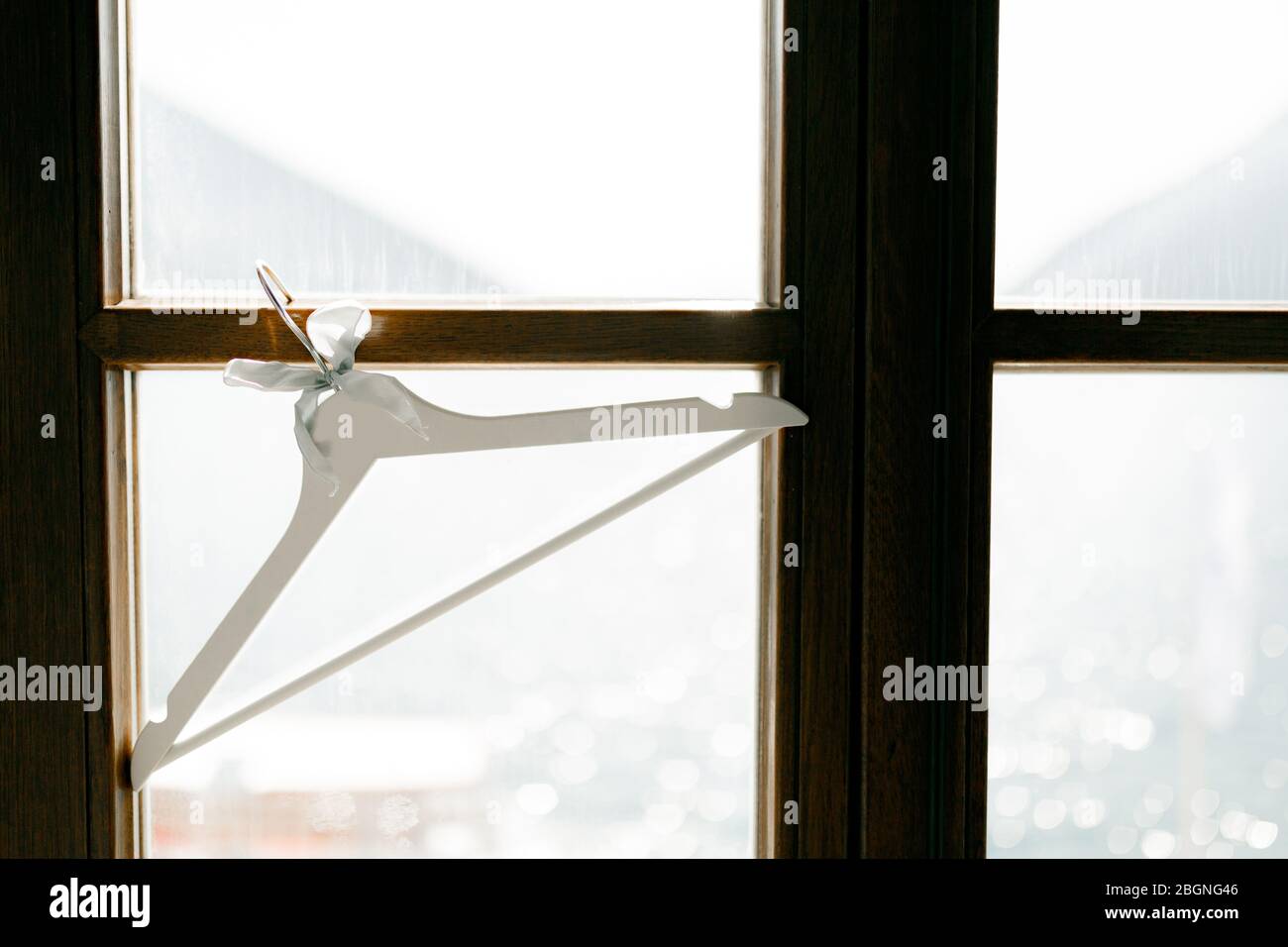 A white coat hanger hangs on the window Stock Photo