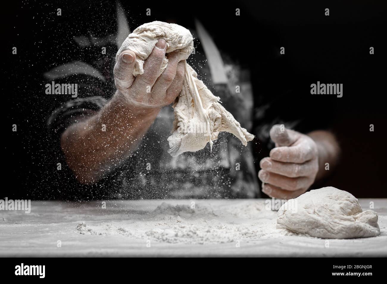 Hands of male baker preparing yeast dough with white flour dust on ...