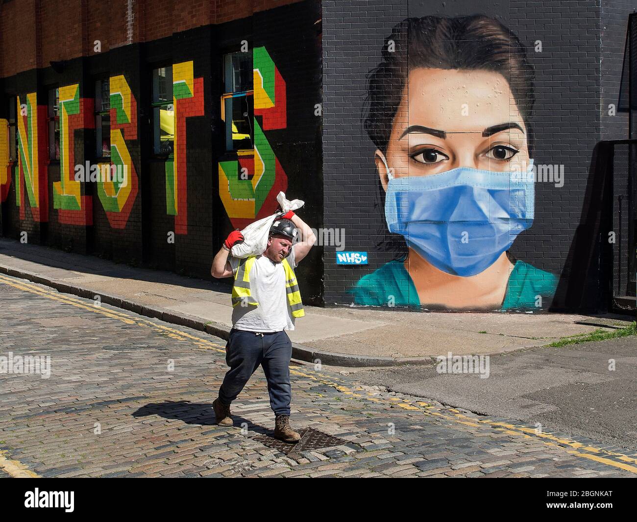 Builder walking past street art supporting the NHS in East London during the corona-virus lockdown. Stock Photo