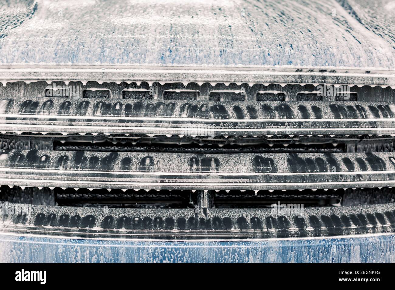 Washing a car, detailing workshop. Close up photo of soapy car radiator ...