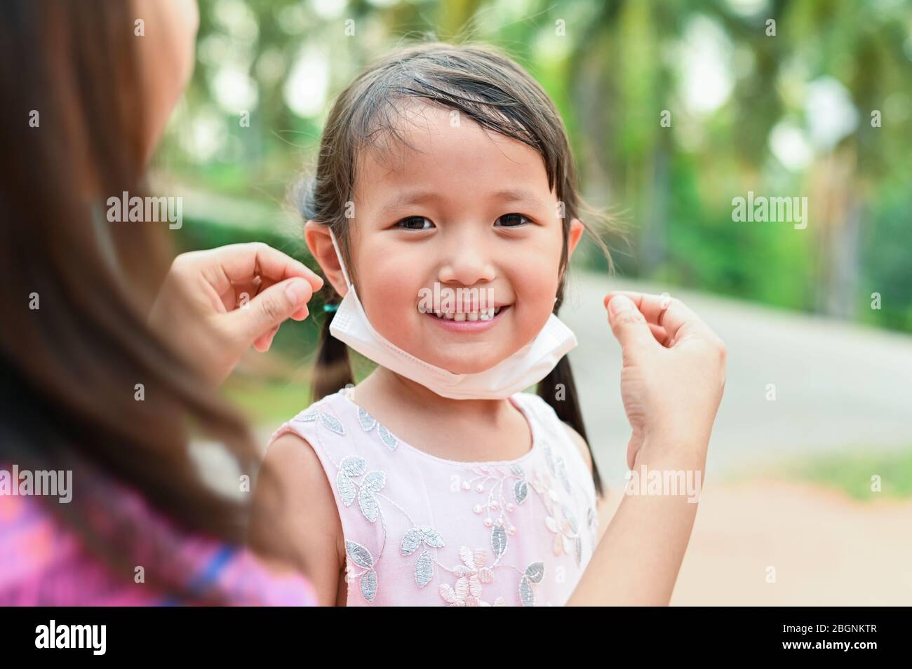 Mother is wearing medical mask for little girl protect herself from Coronavirus when child leave house to public area mom is wearing mask on nose for Stock Photo
