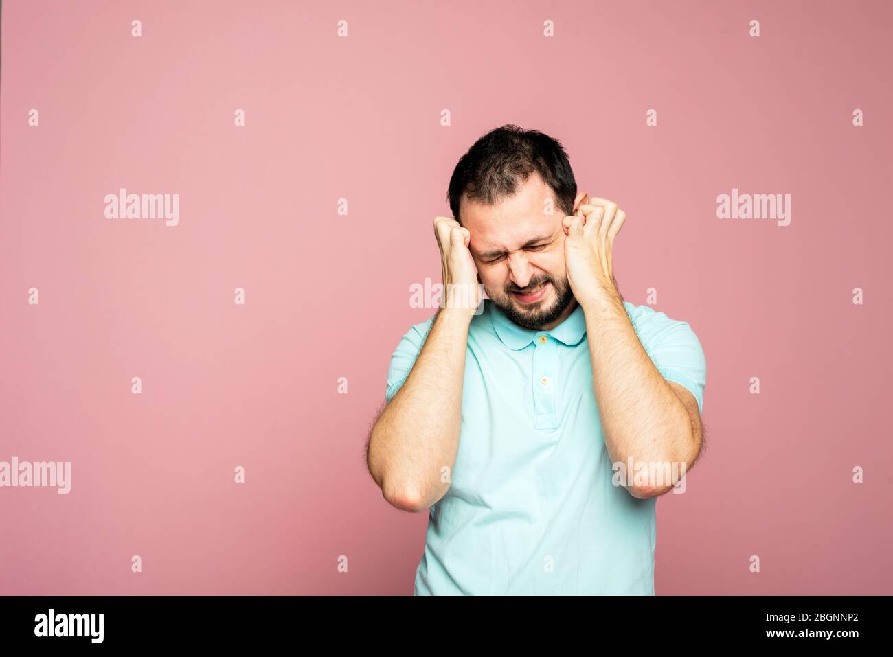 A portrait of a bearded man on the pink background. A man is sad with closed eyes. Sorry. Stock Photo