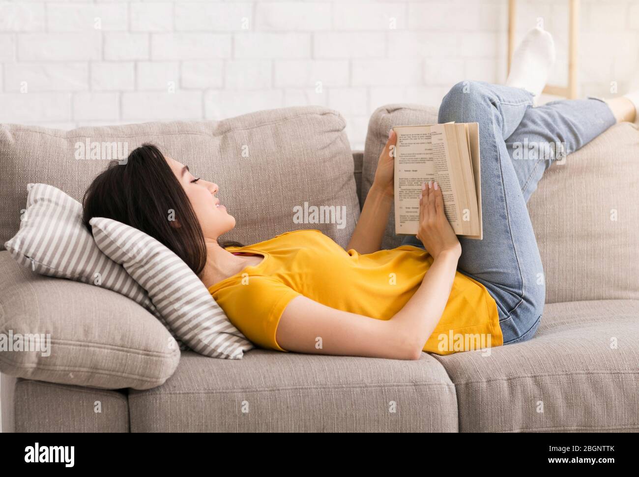 Quarantine leisure activities. Intelligent woman reading interesting book on sofa at home Stock Photo