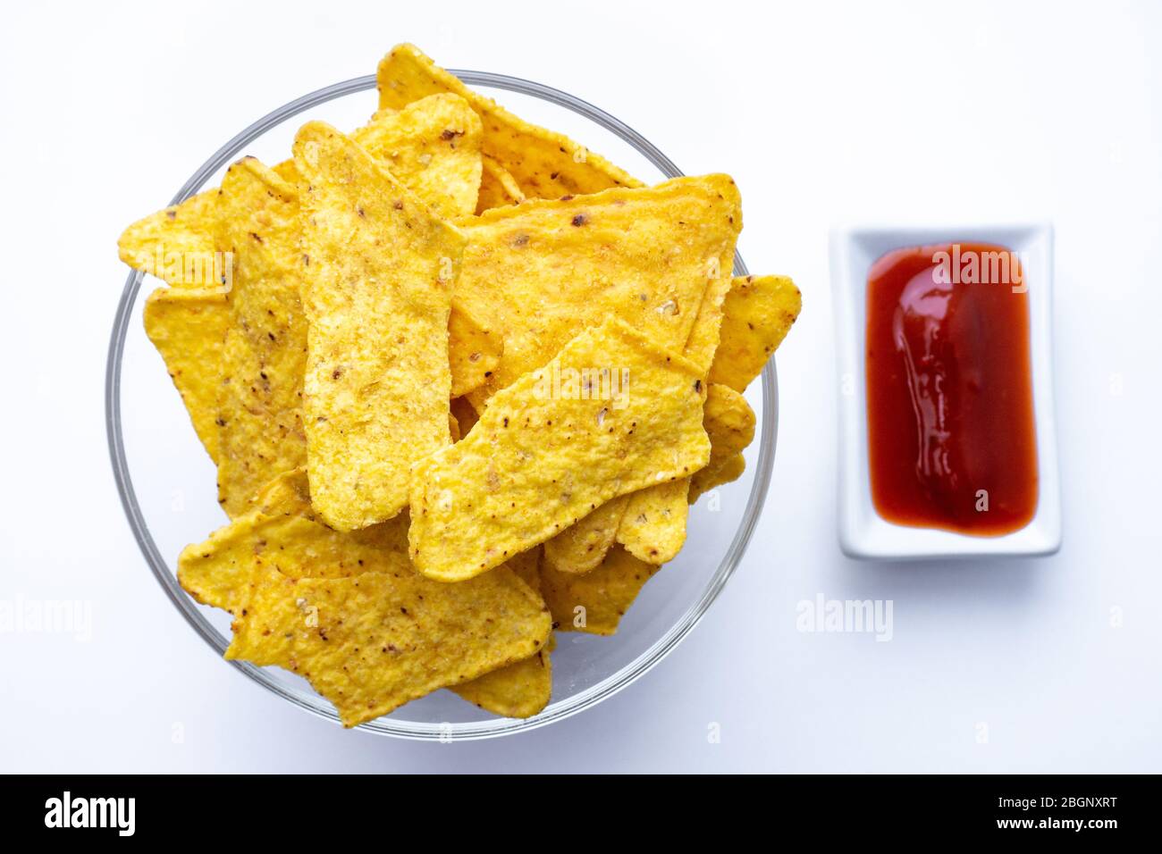 Triangular corn chips, mexican nachos with sauces tomato ketchup, close