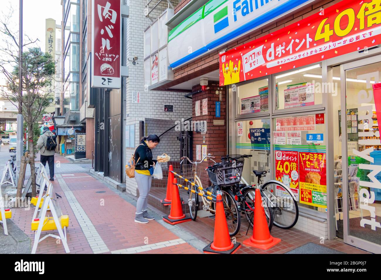A woman in black sweater stands in front of Family mart store near Ueno station in Tokyo, Japan February 8,2020 Stock Photo
