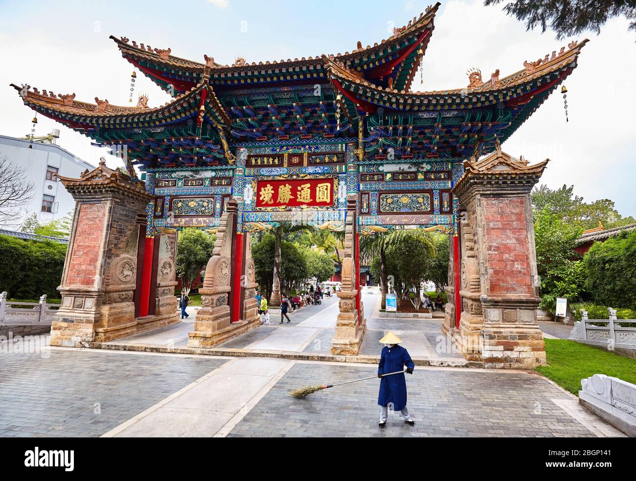 Kunming, China - September 20, 2017: Sweeper in front of ancient Buddhist Yuantong Temple entrance gate. Stock Photo