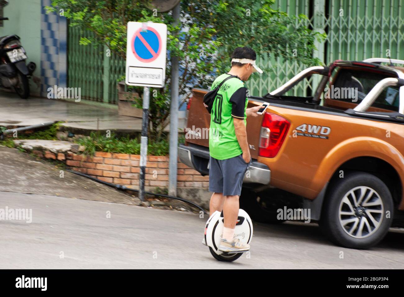 YALA, THAILAND - August 16 : Travelers thai men people playing smart mobile phone and riding electric unicycle monocycle wheel on road tour at Betong Stock Photo