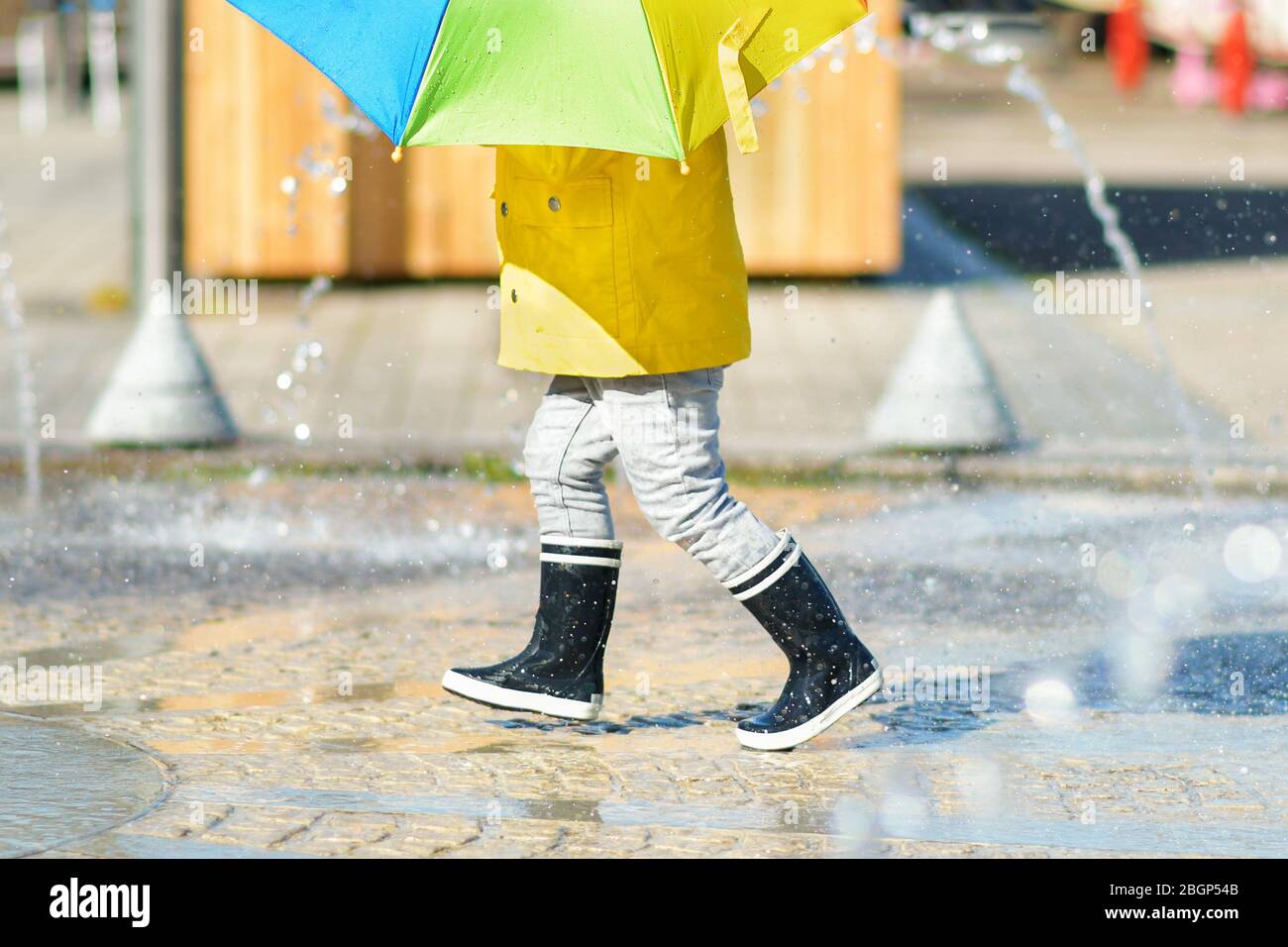 Girl in black rubber boots running through the puddles Stock Photo