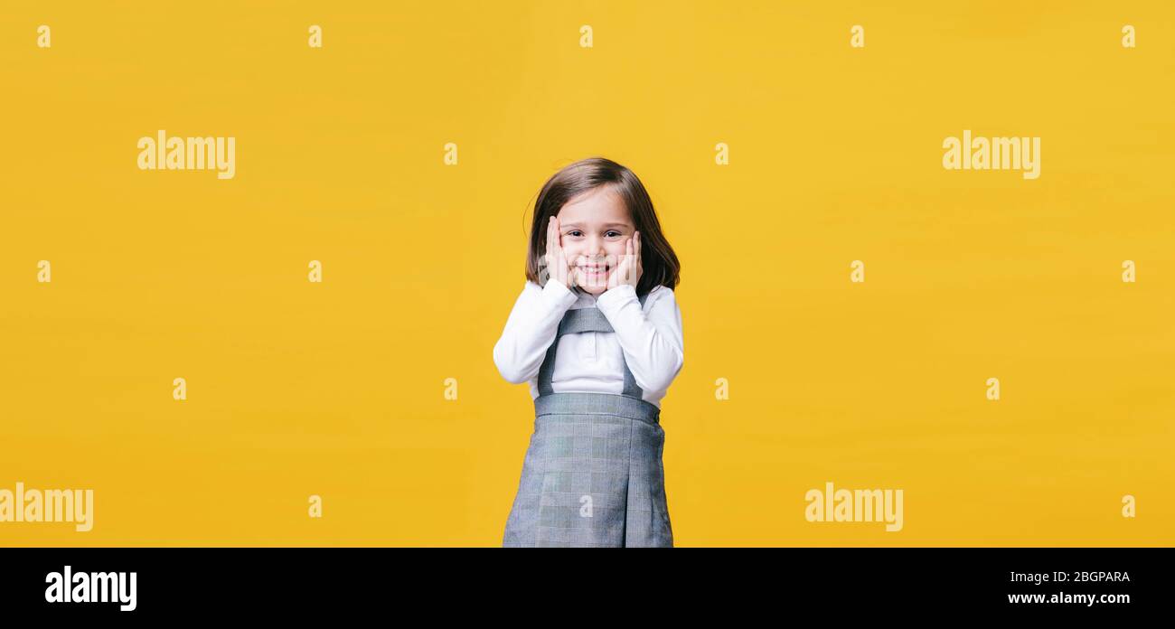 A happy little girl laughing surprised with her hands on her face in ...